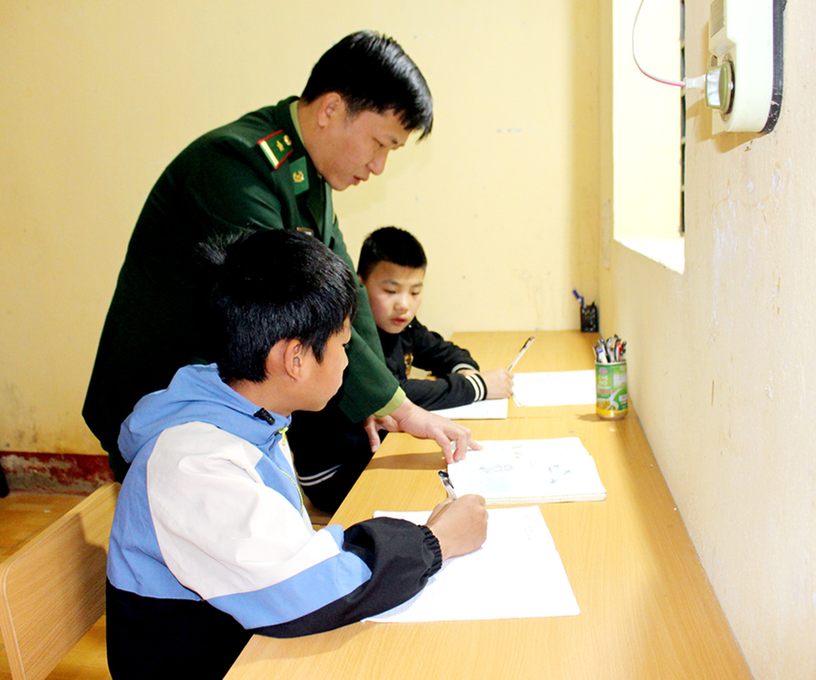 Cán bộ Đồn Biên phòng Tùng Vài (Quản Bạ) hướng dẫn các con nuôi học bài.