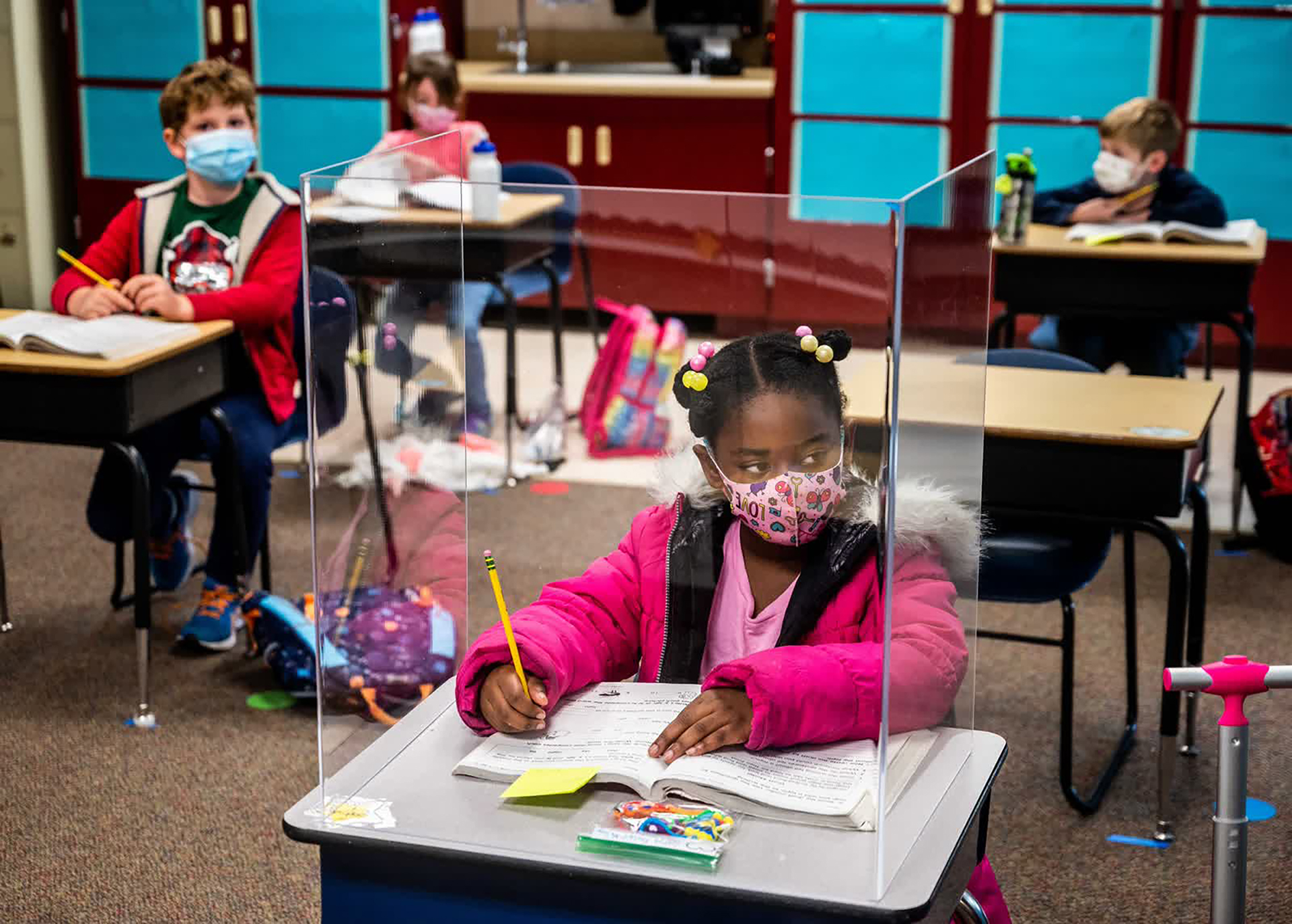 Bàn học của em Sophia Frazier (học sinh lớp 1, Trường tiểu học Two Rivers tại bang California, Mỹ) được che chắn bằng vách ngăn nhựa. Những bàn học gần với bàn giáo viên nhất đều có vách ngăn như vậy.
