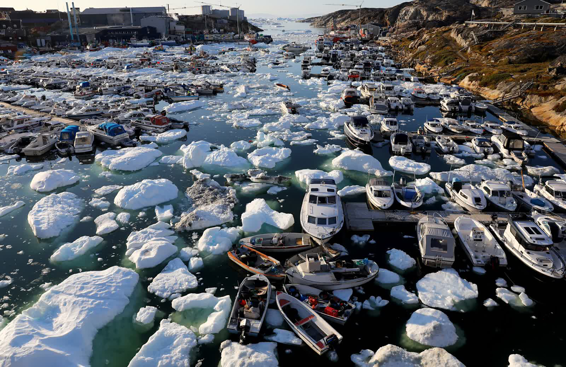 Băng nổi quanh tàu thuyền tại một cảng ở Ilulissat, Greenland. Khi biến đổi khí hậu làm hành tinh nóng lên, lượng băng mất đi đã tăng lên nhanh chóng. Theo một nghiên cứu được công bố trên tạp chí Cryosphere, Trái đất đã mất đi 28 nghìn tỷ tấn băng kể từ giữa những năm 1990.