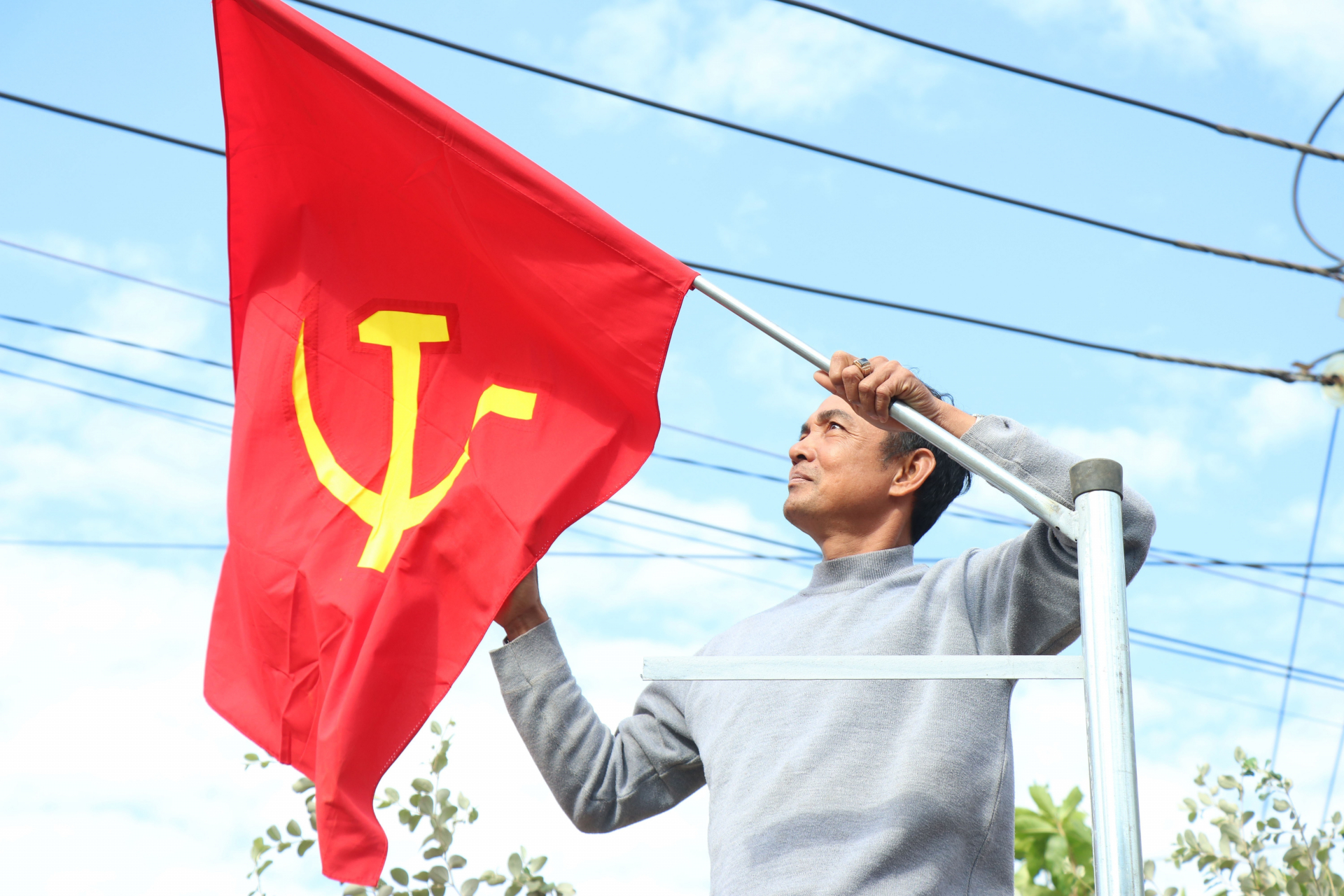 Người dân treo cờ trên tuyến đường chính của xã Cư Mgar, huyện Cư Mgar, tỉnh Đắk Lắk.